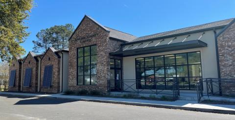 Brick building with large windows under a clear blue sky.